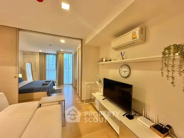 Modern living room with TV and air conditioning, connected to a stylish bedroom.