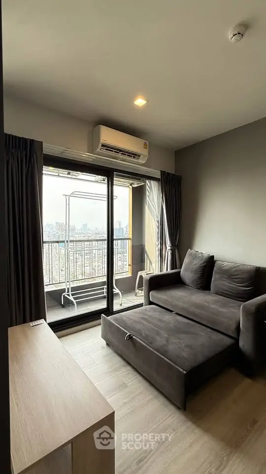 Modern living room with balcony and city view, featuring sleek furniture and air conditioning.
