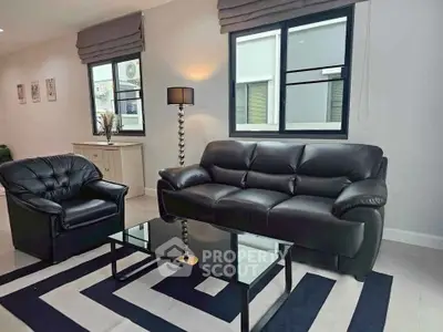 Modern living room with black leather sofa and armchair, glass coffee table, and stylish decor.