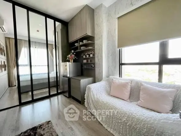 Modern living room with cozy sofa, large windows, and stylish decor in a bright apartment.