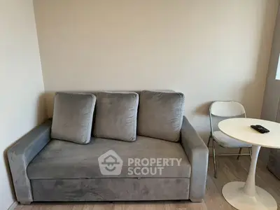Cozy living room with plush gray sofa and modern round table, perfect for relaxation.