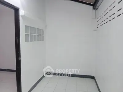 Minimalist white tiled room with glass block window feature