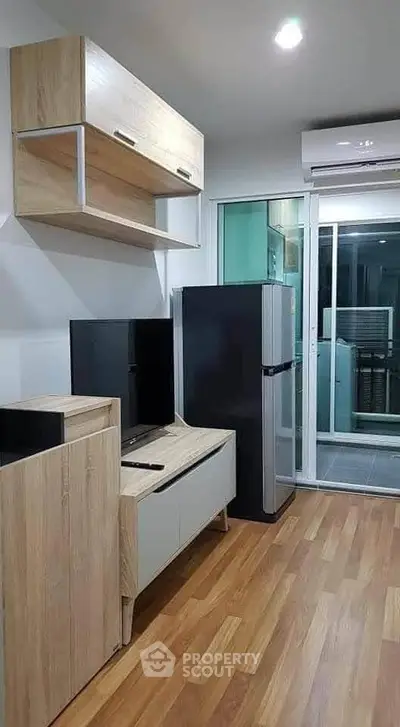 Modern living room with wooden flooring, sleek TV unit, and balcony access in a stylish apartment.