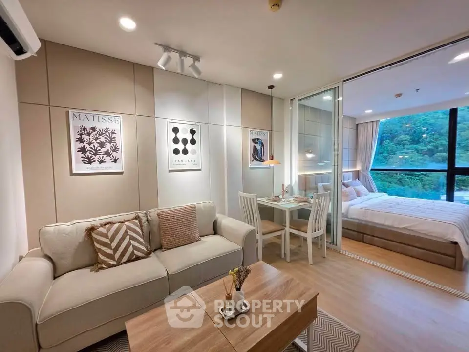 Modern open-plan living room with cozy bedroom and scenic view, featuring stylish decor and natural light.