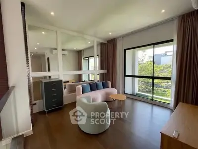Spacious living room with large windows and modern furniture, offering a serene garden view.