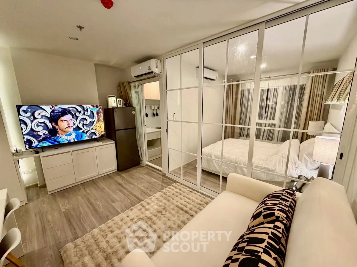 Modern studio apartment with glass partition, cozy living area, and stylish decor.