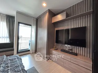 Modern bedroom with sleek wooden furniture and large TV, featuring a cozy balcony view.