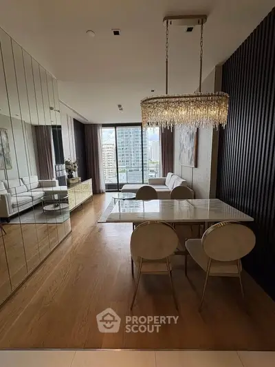 Luxurious modern living room with elegant chandelier and city view, featuring mirrored walls and stylish furniture.