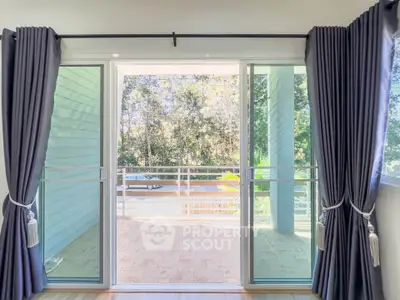 Spacious balcony with sliding glass doors and lush greenery view