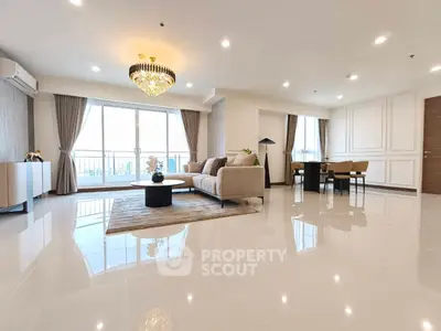 Spacious modern living room with elegant chandelier and large windows offering natural light.