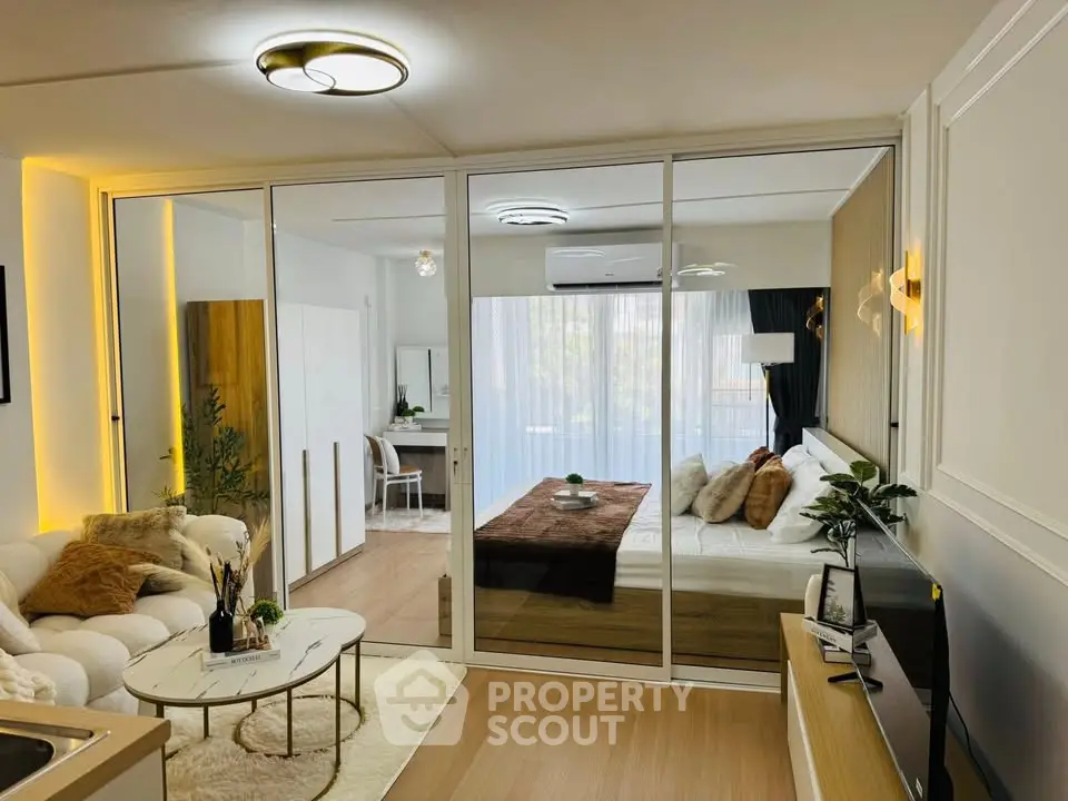 Modern studio apartment with open layout, featuring cozy living area and stylish bedroom separated by glass partition.