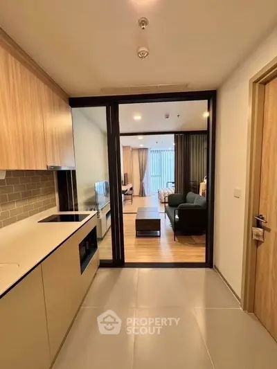 Modern open-layout kitchen leading to a spacious living room with stylish decor and natural light.