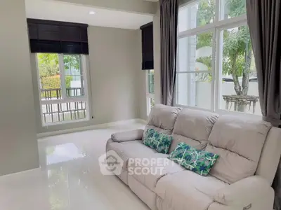Bright living room with large windows and cozy sofa, offering a serene garden view.