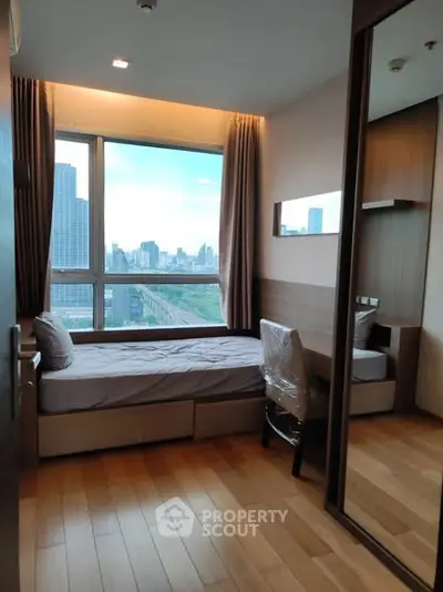 Modern bedroom with city view and wooden flooring in high-rise apartment