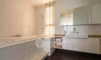 Spacious modern bathroom with elegant marble bathtub and sleek vanity.