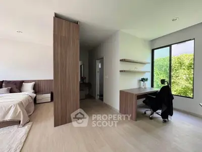 Spacious modern bedroom with study area and large window overlooking greenery.