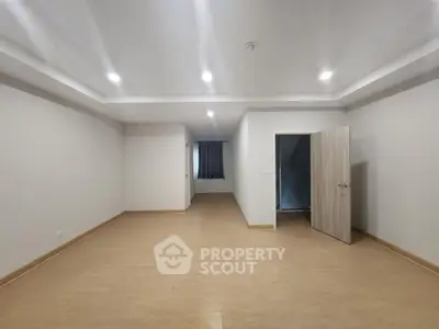Spacious empty room with wooden flooring and recessed lighting