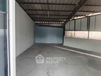 Spacious industrial-style garage with concrete flooring and metal roofing, ideal for storage or workshop use.