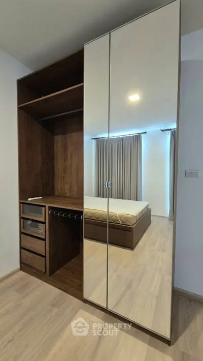 Modern bedroom with sleek mirrored wardrobe and wooden flooring