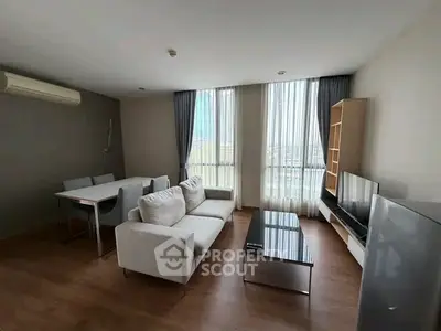 Spacious modern living room with large windows and stylish furniture in a high-rise apartment.