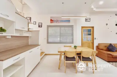 Bright and modern open layout kitchen with adjacent cozy dining space, featuring sleek cabinetry and a comfortable living area.