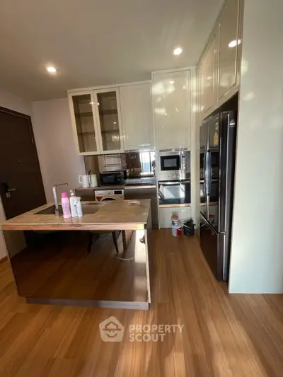 Modern kitchen with sleek appliances and wooden flooring in a stylish apartment.