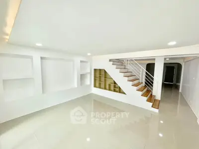 Spacious modern living room with sleek staircase and built-in shelving