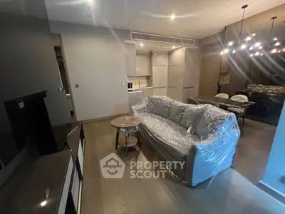 Modern living room with sleek furniture and open kitchen layout in a stylish apartment.