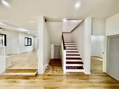 Spacious modern interior with wooden flooring and elegant staircase, perfect for stylish living.