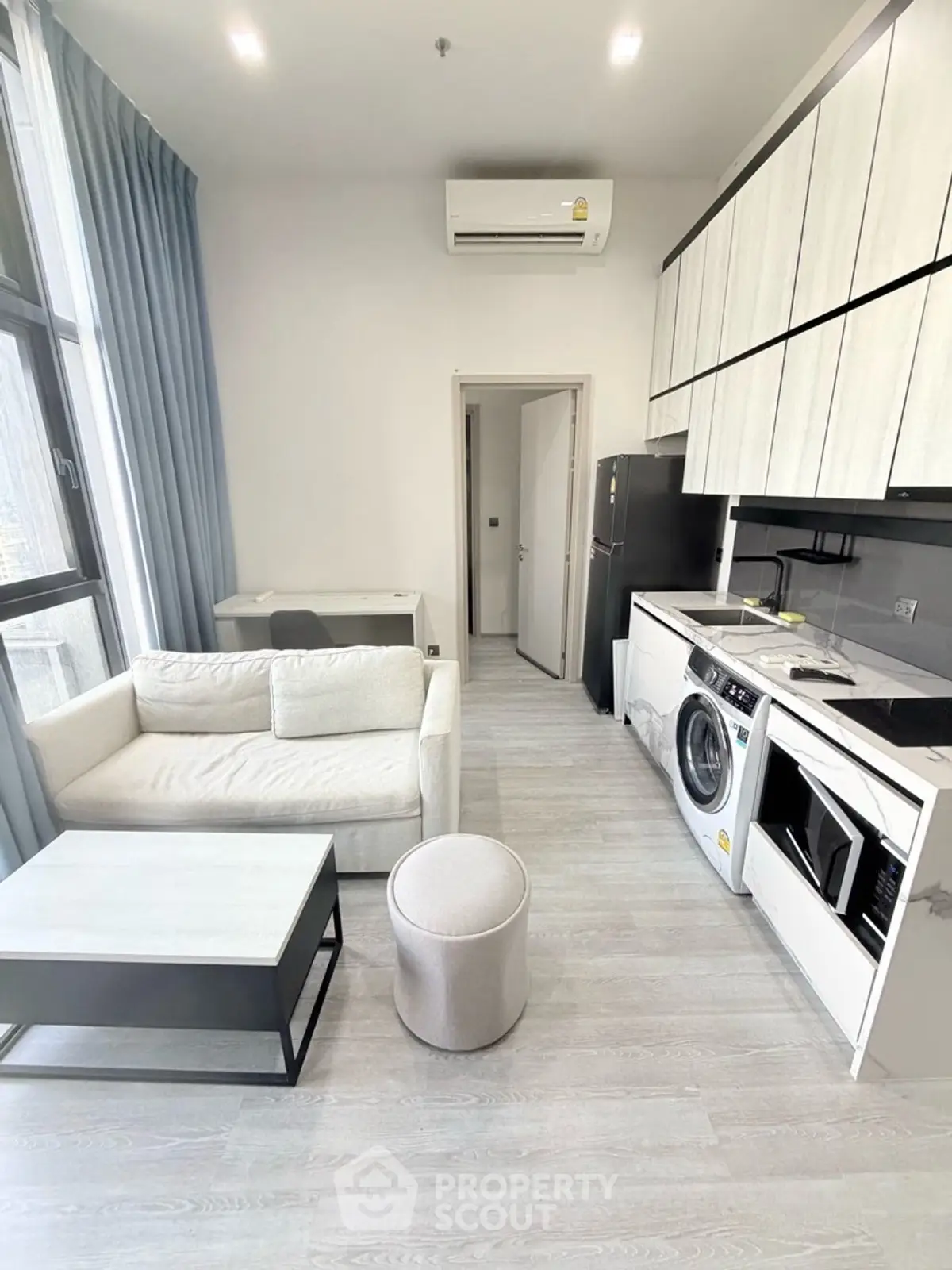 Modern studio apartment with sleek kitchen and cozy living area, featuring a washing machine and air conditioning.
