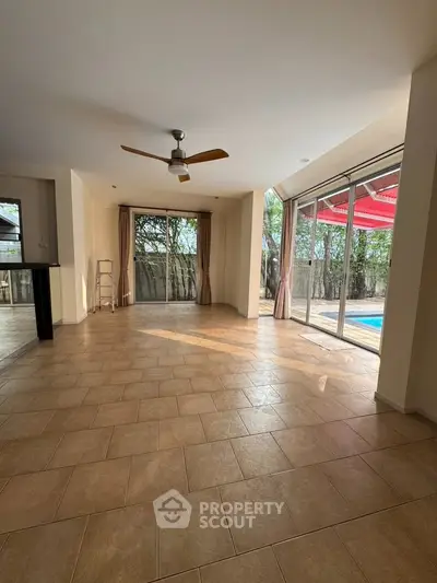 Spacious living room with pool view and ceiling fan, perfect for relaxation.