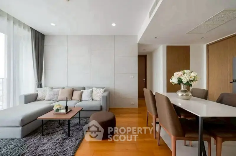 Modern living room with elegant dining area and cozy seating, featuring stylish decor and natural light.