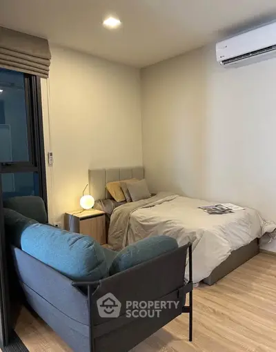 Cozy bedroom with modern decor, featuring a comfortable bed, stylish sofa, and air conditioning for ultimate comfort.