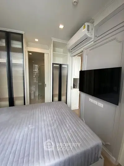 Modern bedroom with sleek design and wall-mounted TV, featuring built-in storage and air conditioning.