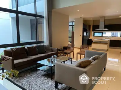 Spacious and modern open-plan living area with plush sofas, sleek kitchen, and abundant natural light, perfect for entertaining and relaxation.