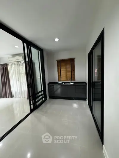 Modern apartment interior with sleek black kitchen cabinets and large windows for natural light.