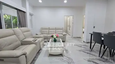 Spacious modern living room with elegant marble flooring and plush beige sofas.