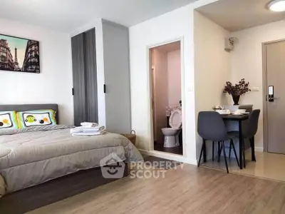 Modern studio apartment with cozy bedroom and dining area, featuring stylish decor and wooden flooring.