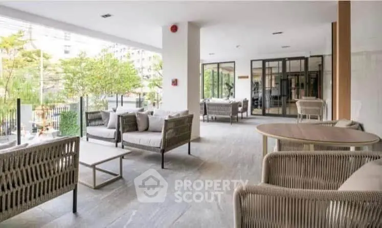 Modern outdoor seating area with stylish furniture and lush greenery in a contemporary building.