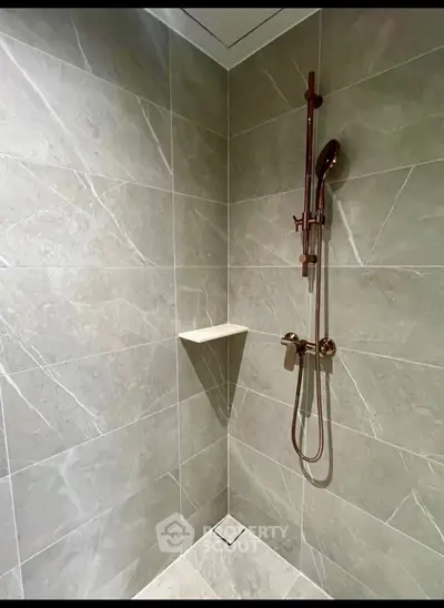 Modern bathroom shower with sleek marble tiles and elegant fixtures.