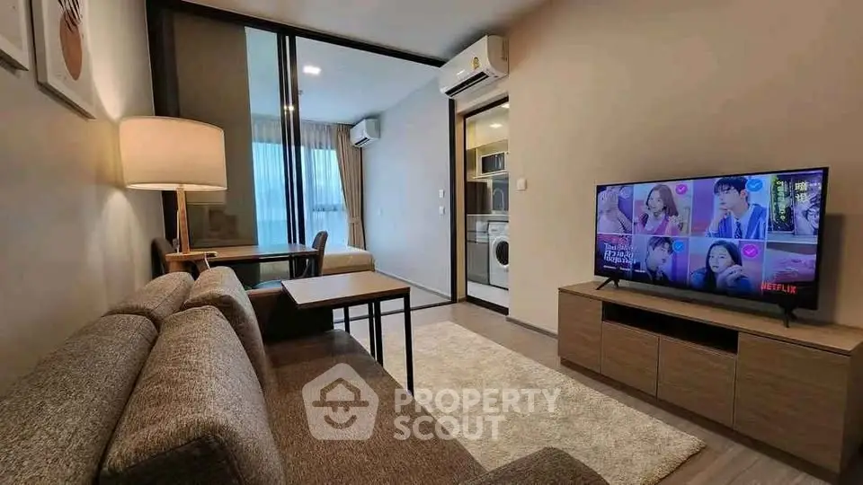 Modern living room with cozy sofa, TV, and open kitchen layout in stylish apartment.
