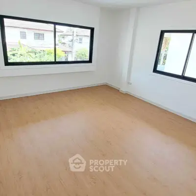 Spacious empty room with large windows and wooden flooring, perfect for customization.