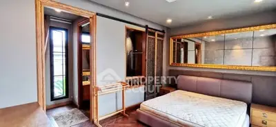 Luxurious bedroom with elegant decor and large mirror, featuring a cozy bed and stylish wooden accents.