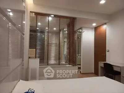 Modern bedroom with sleek design and wooden accents, featuring a cozy workspace.