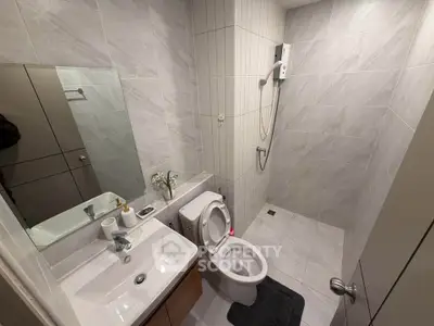 Modern bathroom with sleek design, featuring a shower, toilet, and vanity in a compact space.