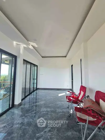 Spacious modern room with large windows and sleek marble flooring, perfect for relaxation and enjoying natural light.