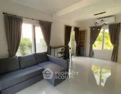 Spacious living room with modern sofa and large windows for natural light.