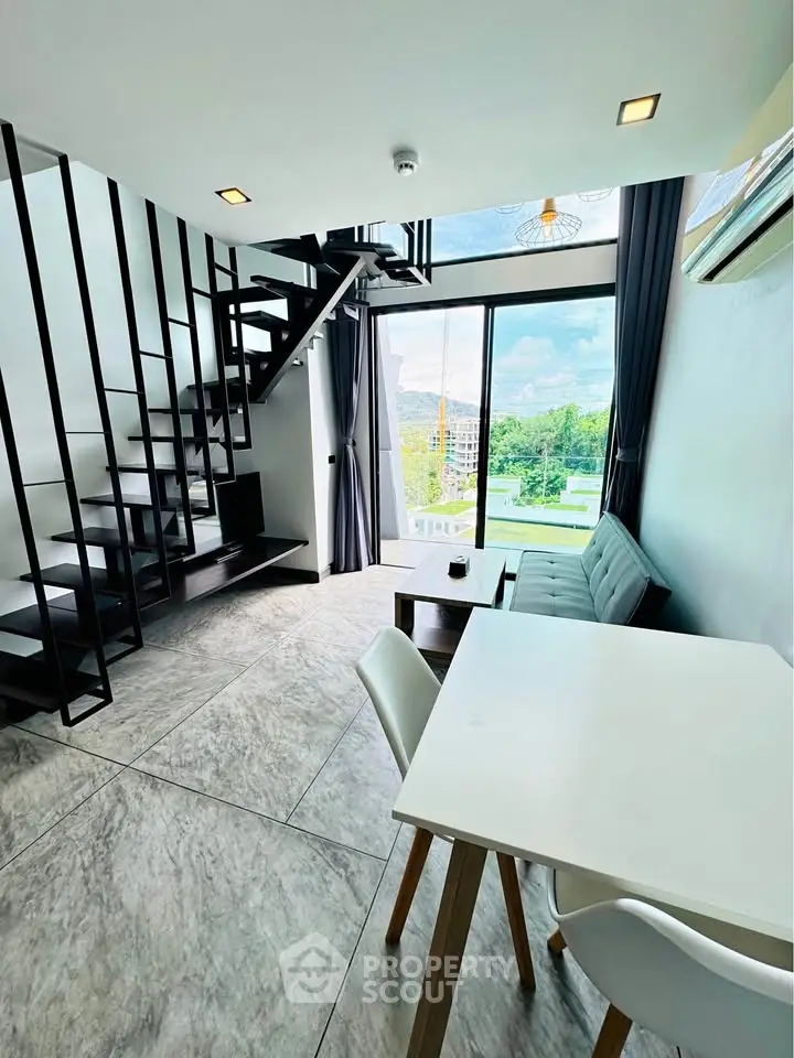Modern duplex living room with staircase and large windows offering scenic views