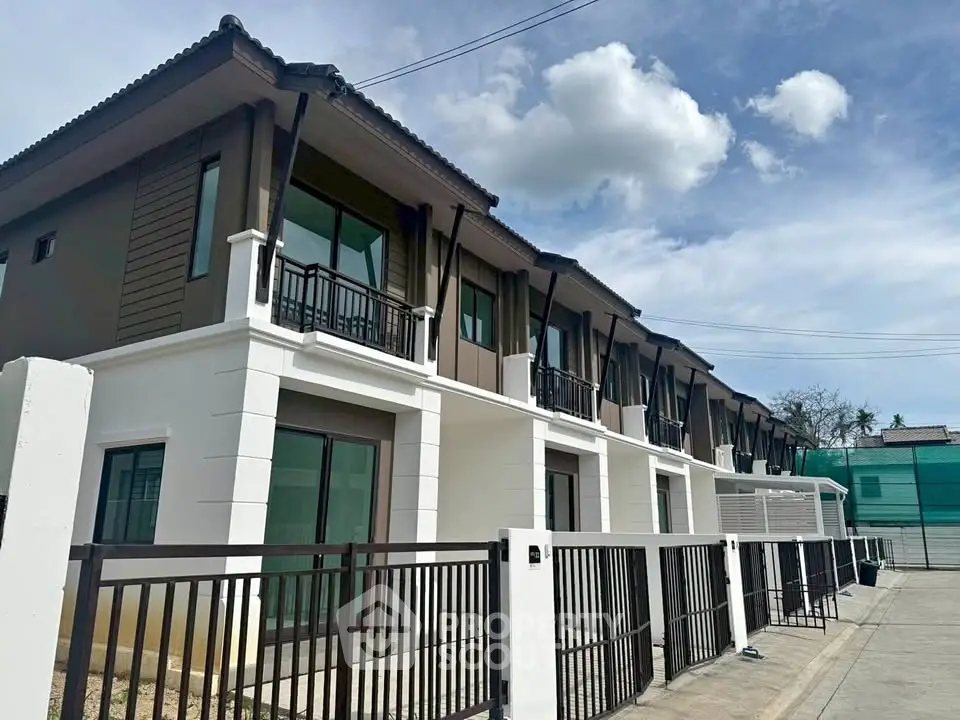 Modern townhouse exterior with sleek design and spacious balconies under a clear blue sky.