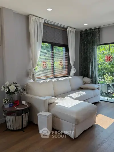 Bright and cozy living room with large windows and elegant decor, perfect for relaxation and entertaining.